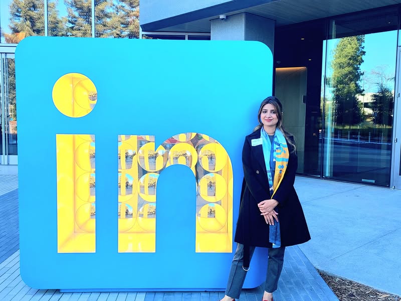 Roshaan Sheikh standing beside the large LinkedIn sign
